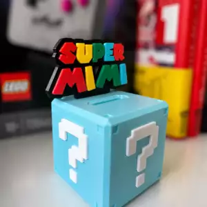 Photo de tirelire boite myst&egrave;re personnalis&eacute;e inspir&eacute;e d'un c&eacute;l&egrave;bre jeu vid&eacute;o. Au dessus de la tirelire est ins&eacute;r&eacute;e une plaque affichant le nom "Super Mimi"