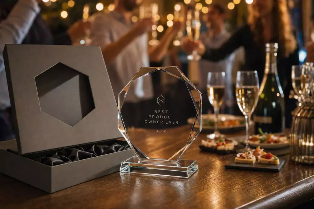 Trophée en verre octogonal gravé d'une phrase et d'un prénom, présenté dans son écrin lors d'un pot de départ
